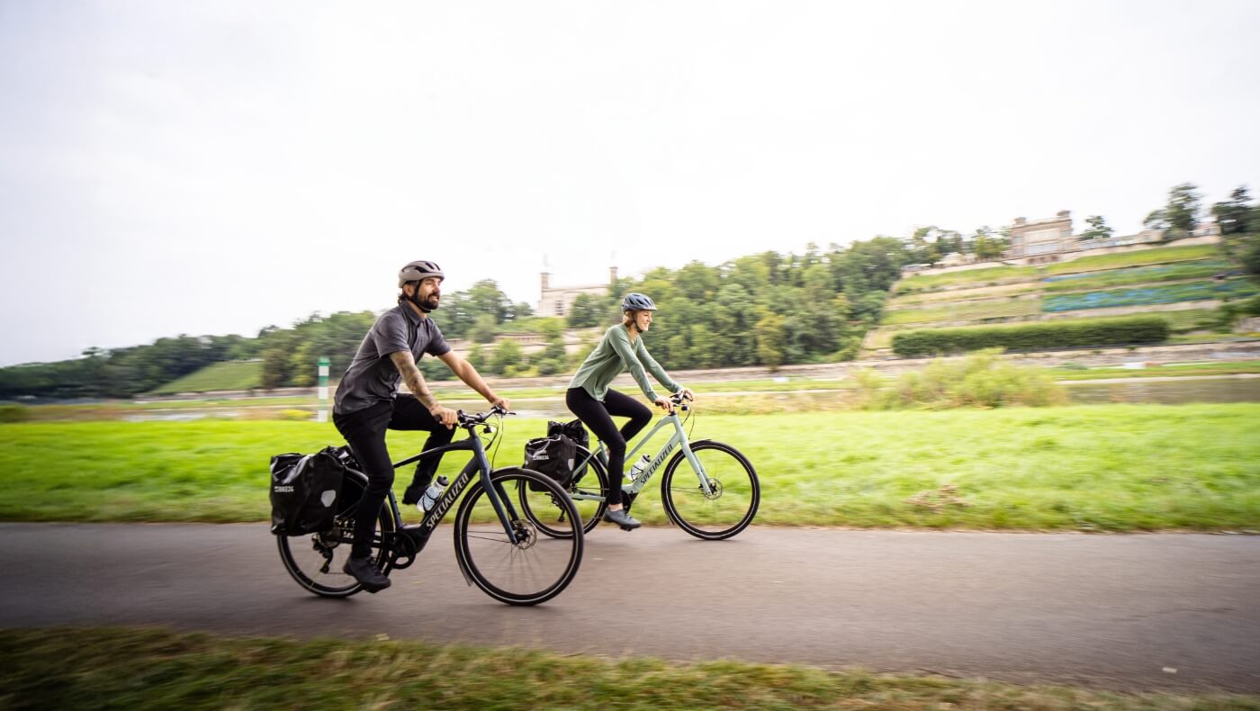 Chico y chica paseando por un pueblo con un bici eléctrica