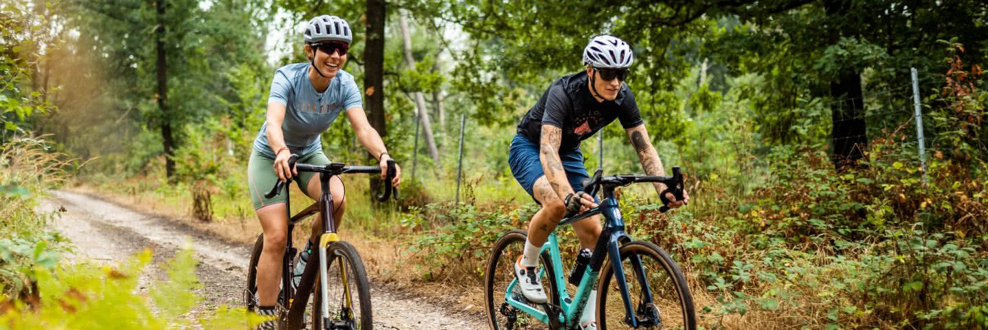 Man and woman on gravel bikes in a wood