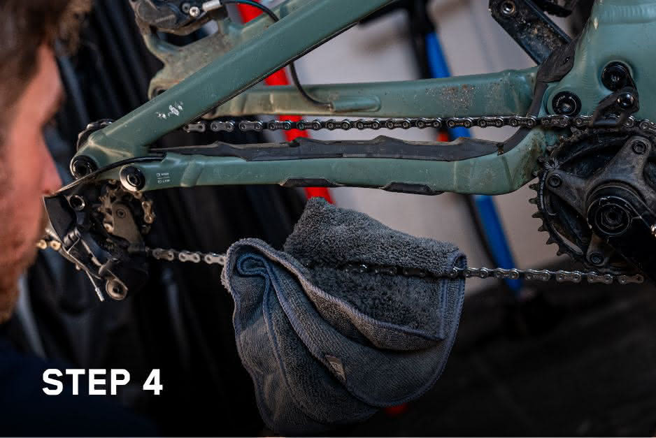 Detailed view of how chain cleaner is wiped off the bicycle chain with a soft cloth