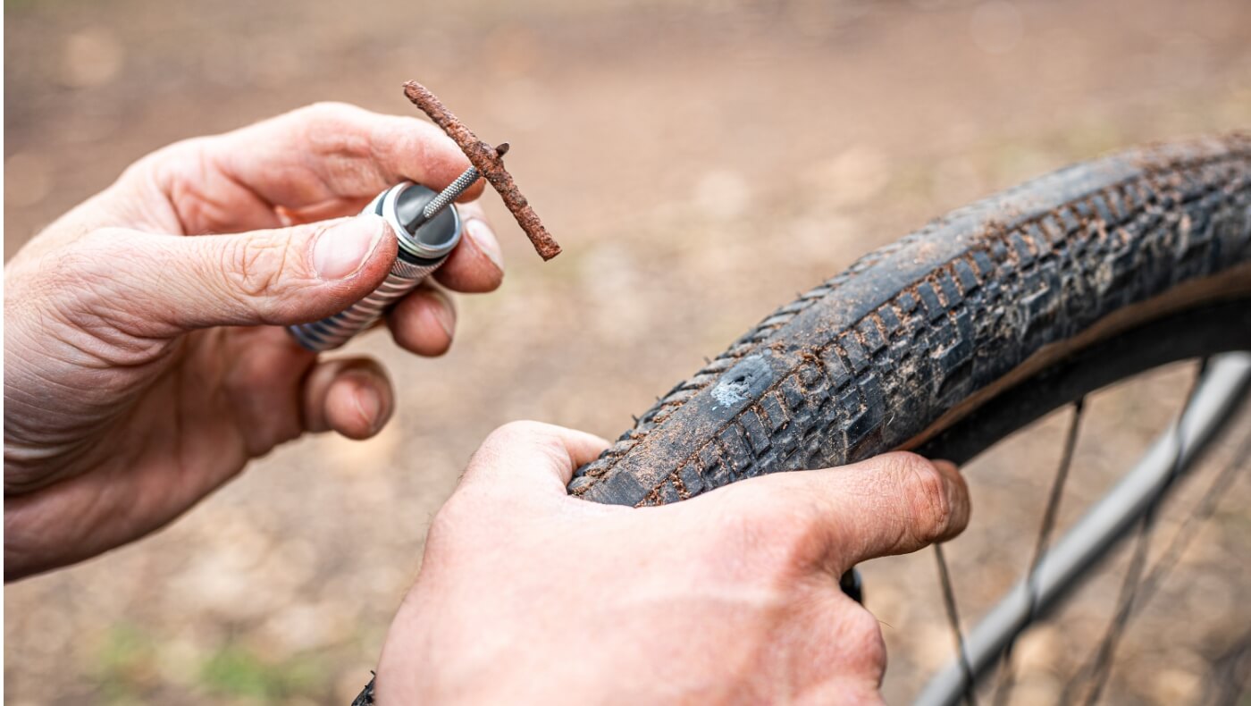 Een persoon repareert een Tubeless band met een rubberen plug.