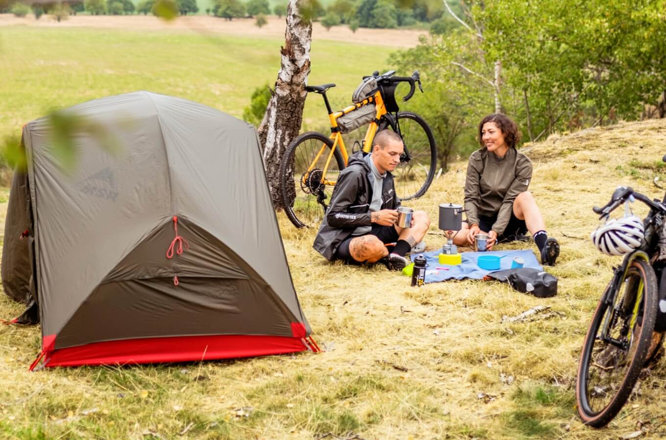 Paar rust uit naast hun tent tijdens het bikepacken