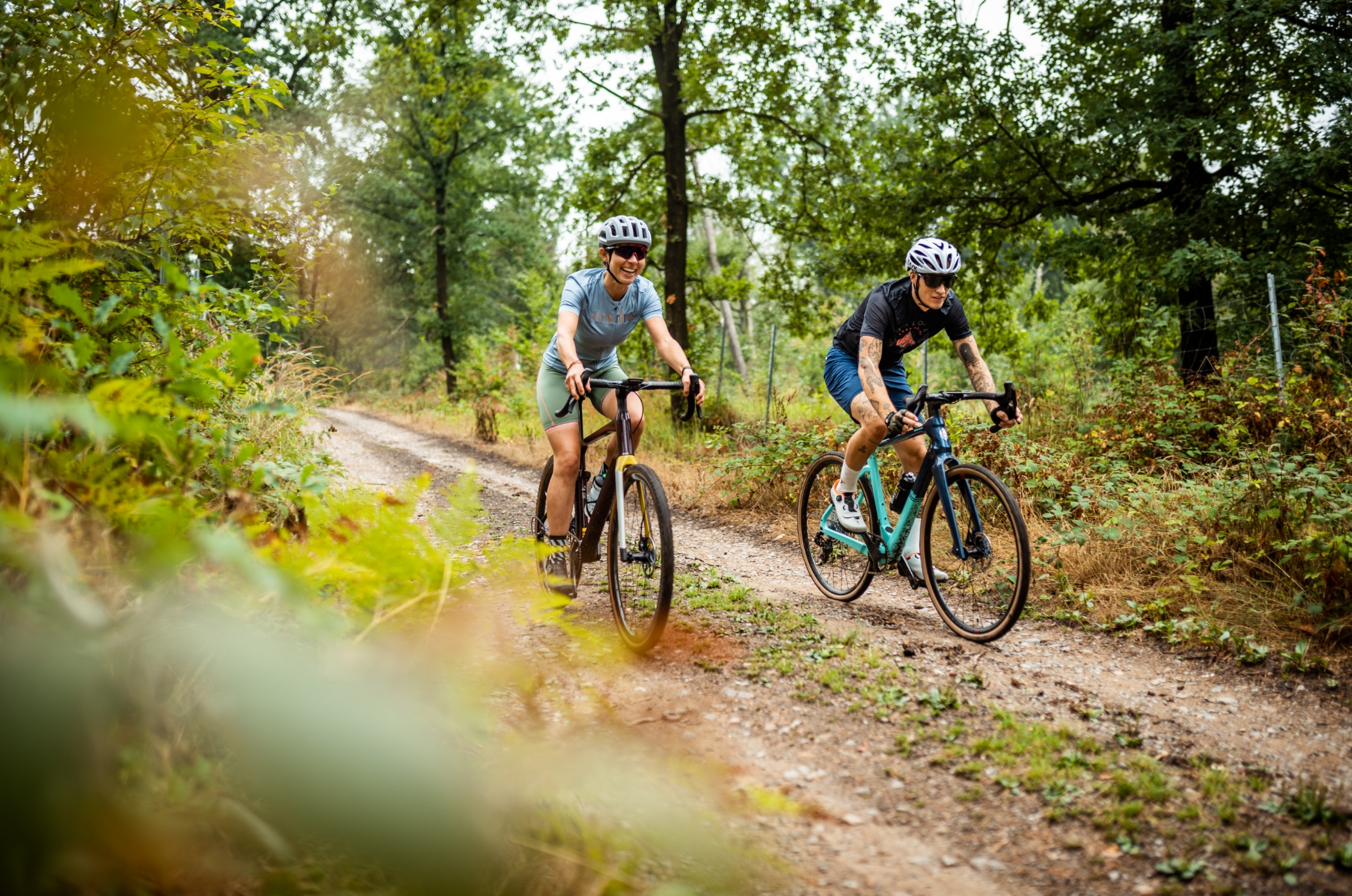 A couple is riding their gravel bikes on a forest road