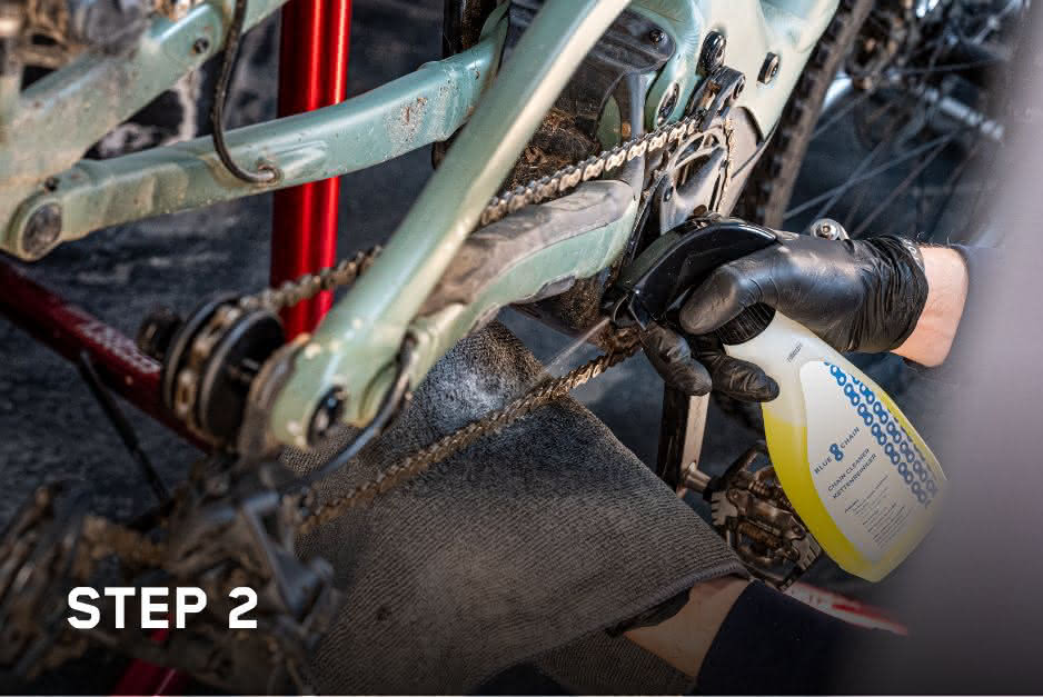 Close-up of a person applying chain cleaner to a bicycle chain