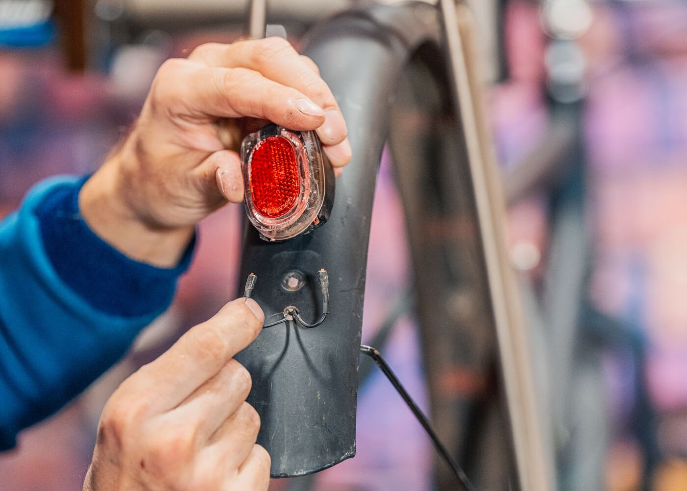 Close-up van een persoon die het achterlicht aansluit op een kabel die door het spatbord loopt.