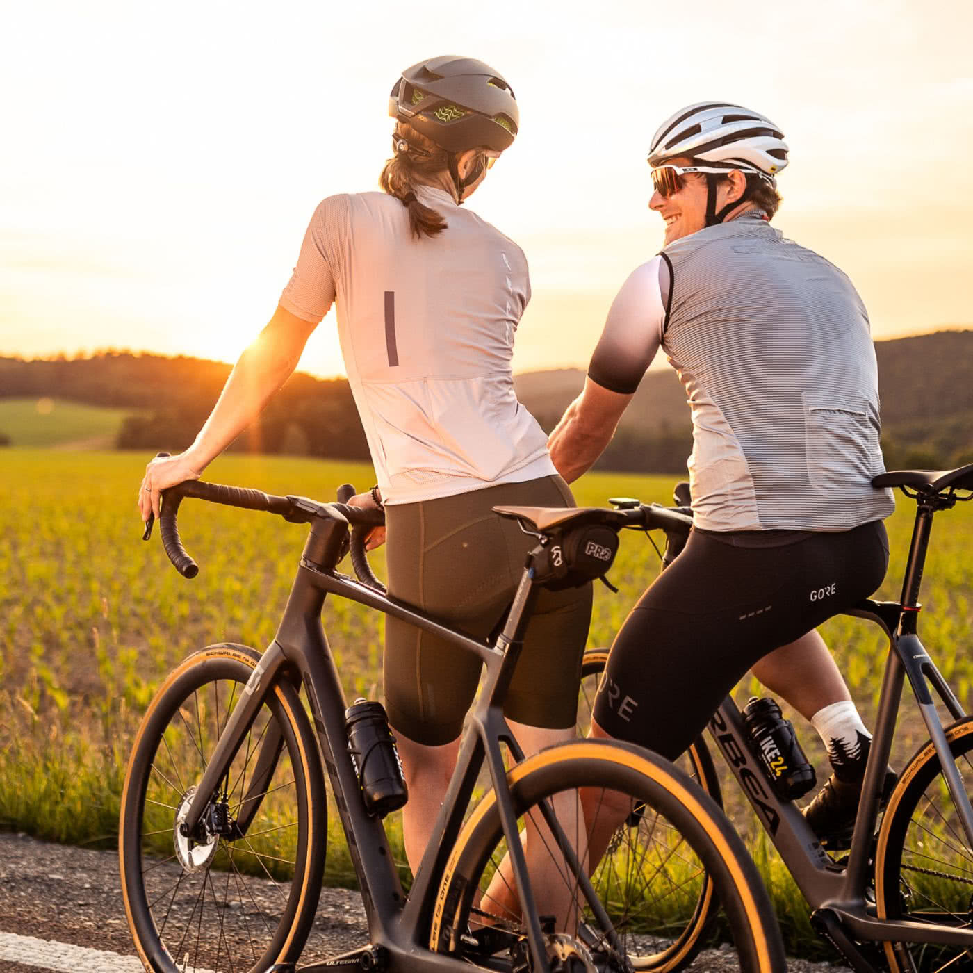 Man and woman on road bikes look into the sunset